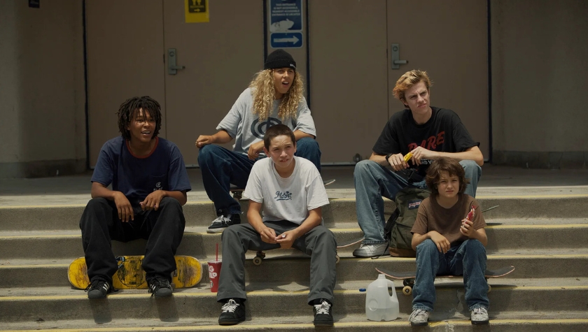 Group of young skateboarders sitting on steps outside a building in Mid90s