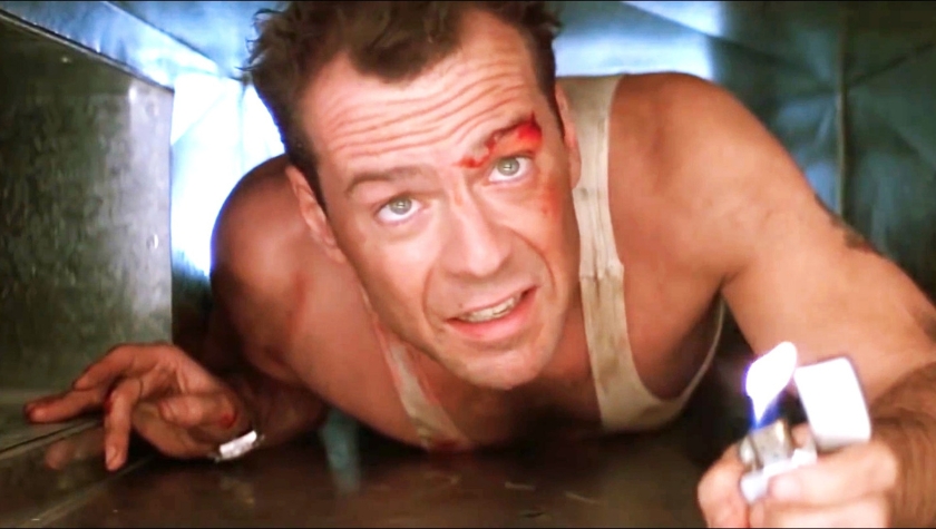 Bruce Willis as John McClane crawling through a ventilation shaft in Die Hard, battered and bloodied