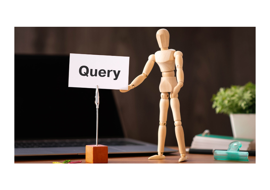a wooden figurine gesturing towards a white card displaying the word Query. A laptop lays on the desk in the background