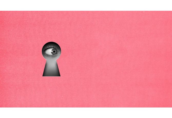 Close-up of a human eye looking through a keyhole on a pink background