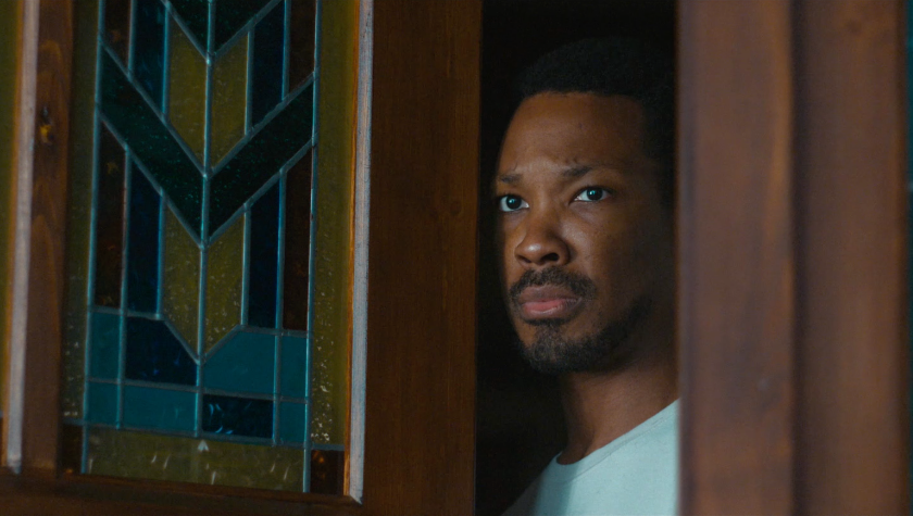 Corey Hawkins peers out of his front door in The Man in My Basement