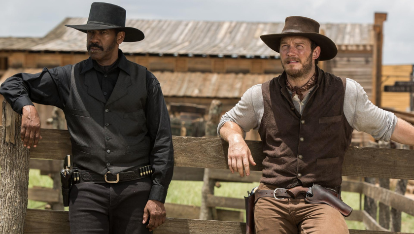 Denzel Washington and Chris Pratt lean against a wooden fence in The Magnificent Seven
