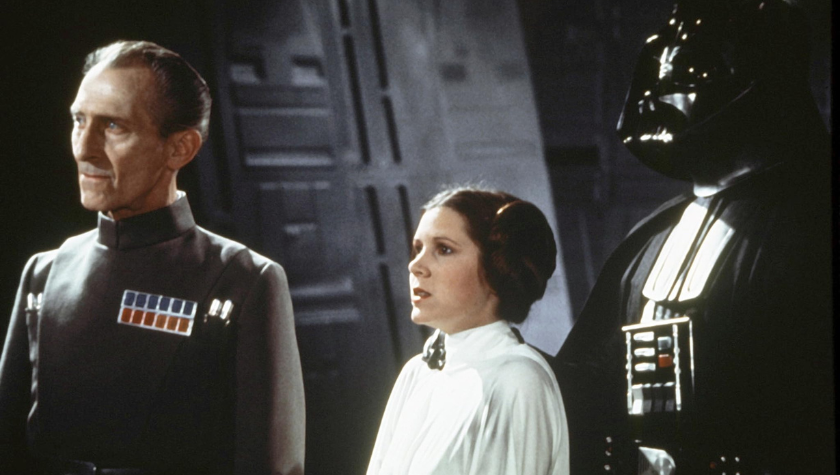 Peter Cushing stands next to James Earl Jones_David Prowse as he holds Carrie Fisher still by her neck. They look out at a planet in Star Wars: Episode IV - A New Hope