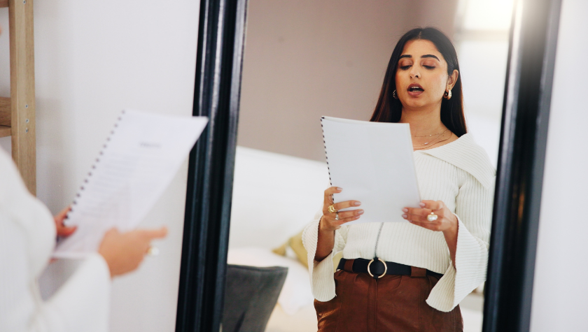 Woman reading her dialogue out loud to her reflection