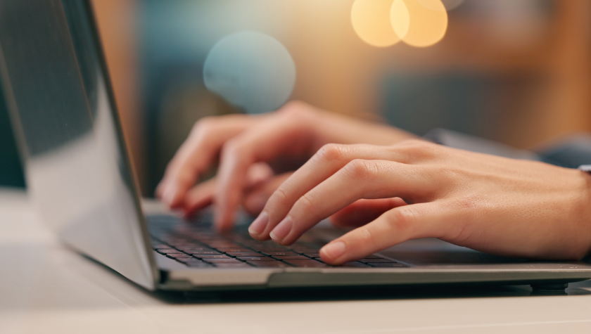 close-up of hands typing on a laptop